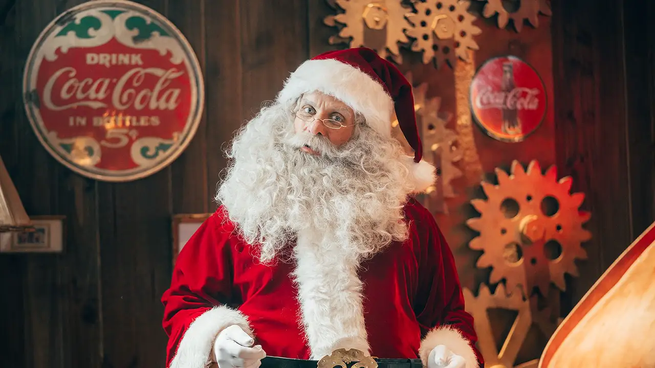 Papá Noel junto a un cartel antiguo de Coca-Cola