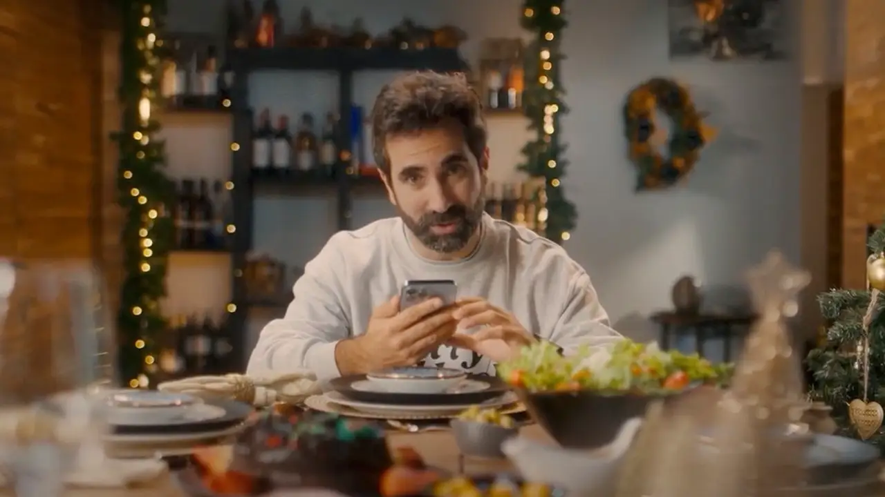 Un hombre mira su móvil en una cena de Navidad